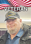 Portrait of a man in a Veteran cap under an American flag graphic with the word VETERAN above him.