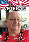 Portrait of an older man in a red shirt and beaded necklace with a U.S. flag and the word Veteran above him.