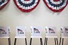 Row of voting booths with VOTE signs beneath red, white and blue bunting.