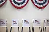 Row of voting booths with VOTE signs beneath red, white and blue bunting.