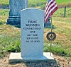 Gravestone for Isaac Munson with an American flag and memorial medallion in a cemetery.