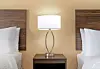 Hotel room with two beds, wooden headboards, and a bedside lamp centered between them.