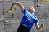 Tennis player in a blue shirt reaches up to serve on an outdoor court.