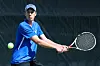 Tennis player in blue prepares a forehand as a tennis ball approaches.