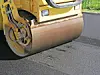 Close-up of a road roller pressing fresh asphalt on a paved road.