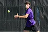 Tennis player in purple shirt preparing to hit a ball during practice.