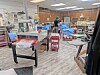 Interior of a sewing workshop with tables, sewing machines, fabric, and supplies.