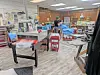 Interior of a sewing workshop with tables, sewing machines, fabric, and supplies.