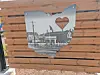 Ohio-shaped metal plaque with a heart cutout mounted on a wooden wall.