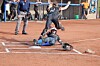 Softball player slides into base while a fielder attempts a tag on a dirt field.