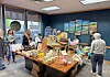 People stand around a table filled with assorted products inside a store.