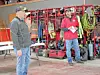 Two firefighters stand near organized racks of firefighting gear and equipment inside a station.