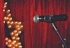 Microphone on a stand in front of red curtains with a glowing star light display.