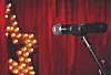 Microphone on a stand in front of red curtains with a glowing star light display.