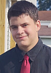 Young man wearing a black shirt and red tie standing outdoors near a house.