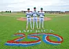 Three baseball players standing on a field behind a large painted 250.