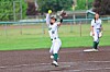 Softball player in white uniform celebrates on the infield with a raised glove.