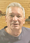Close-up of a man indoors in front of a tan perforated wall.