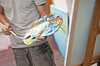 Person holding a paint palette with colorful paint and a brush in a studio.