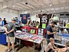 People browsing tables filled with sports memorabilia and collectibles in a convention hall.