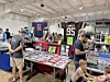 People browsing tables filled with sports memorabilia and collectibles in a convention hall.