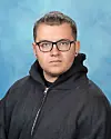 Portrait of a man wearing glasses and a black hoodie against a blue background.