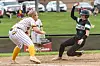 A softball runner slides toward home plate while the catcher waits to tag her.
