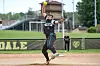 Softball pitcher in black uniform throwing a pitch on a dirt field.
