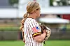 Youth softball player in a striped jersey holding a glove on a field.