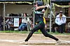 Softball batter swinging in a game on a dirt field, with spectators behind a fence.