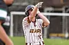 Softball player wearing a helmet and striped jersey raises an arm on the field.