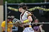 Softball pitcher in maroon and white uniform holds the ball and glove on the field.