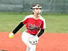 Softball pitcher in a red jersey and white pants throws a ball on a field.