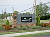 A Carrolton Elementary School sign beside a sidewalk, street, and landscaped planting bed.