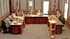 Officials seated around U-shaped tables in a wood-paneled meeting room with flags at the back.