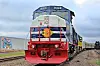 Blue and red freight locomotive on railroad tracks in a rural setting.