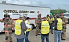 Several workers in reflective vests and helmets stand near a Carroll County, Ohio hazardous utility trailer outdoors.