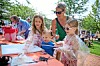Children and adults stand around an outdoor craft table with paint supplies at Yorktown Lanes in Cleveland.