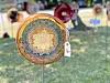 A patterned decorative metal plate hangs in the foreground with other plates behind it outdoors.