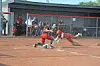A softball player slides into home plate as the catcher tries to make a tag.