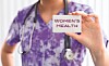 Healthcare worker holding a card that says Women's Health.