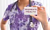 Healthcare worker holding a card that says Women's Health.