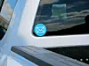 Blue envelope sticker on a silver vehicle's rear window beside the side mirror.
