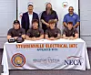 Group posing behind a Steubenville Electrical IATC banner with caps and hard hats at an indoor event.
