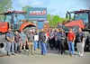 Group standing in front of two red Case IH tractors and a Case IH sign outdoors.