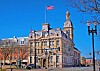 Historic stone building with a clock tower and an American flag flying above it.