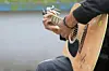 Close-up of hands playing an acoustic guitar while seated.