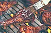Chicken legs grilling on a wire rack over open flames.