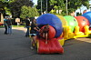 People standing next to colorful inflatable tube structures on a paved outdoor path.