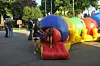 People standing next to colorful inflatable tube structures on a paved outdoor path.